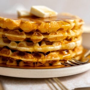 Stack of buttermilk waffles with syrup and butter.