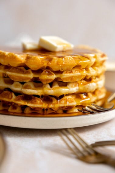 Stack of buttermilk waffles with syrup and butter.