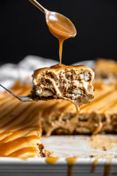 Slice of dulce de leche tiramisu being drizzled with caramel sauce on top.