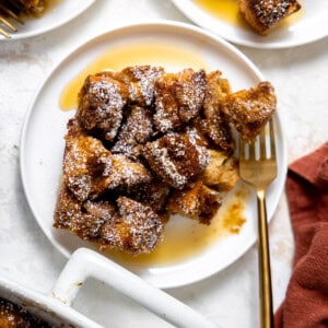 French toast casserole served on a white plate and drizzled with maple syrup.