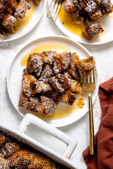 French toast casserole served on a white plate and drizzled with maple syrup.