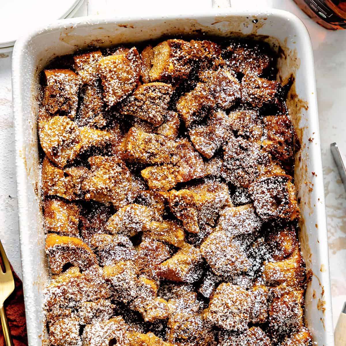 Baked French toast casserole topped with a sprinkling of powdered sugar. 