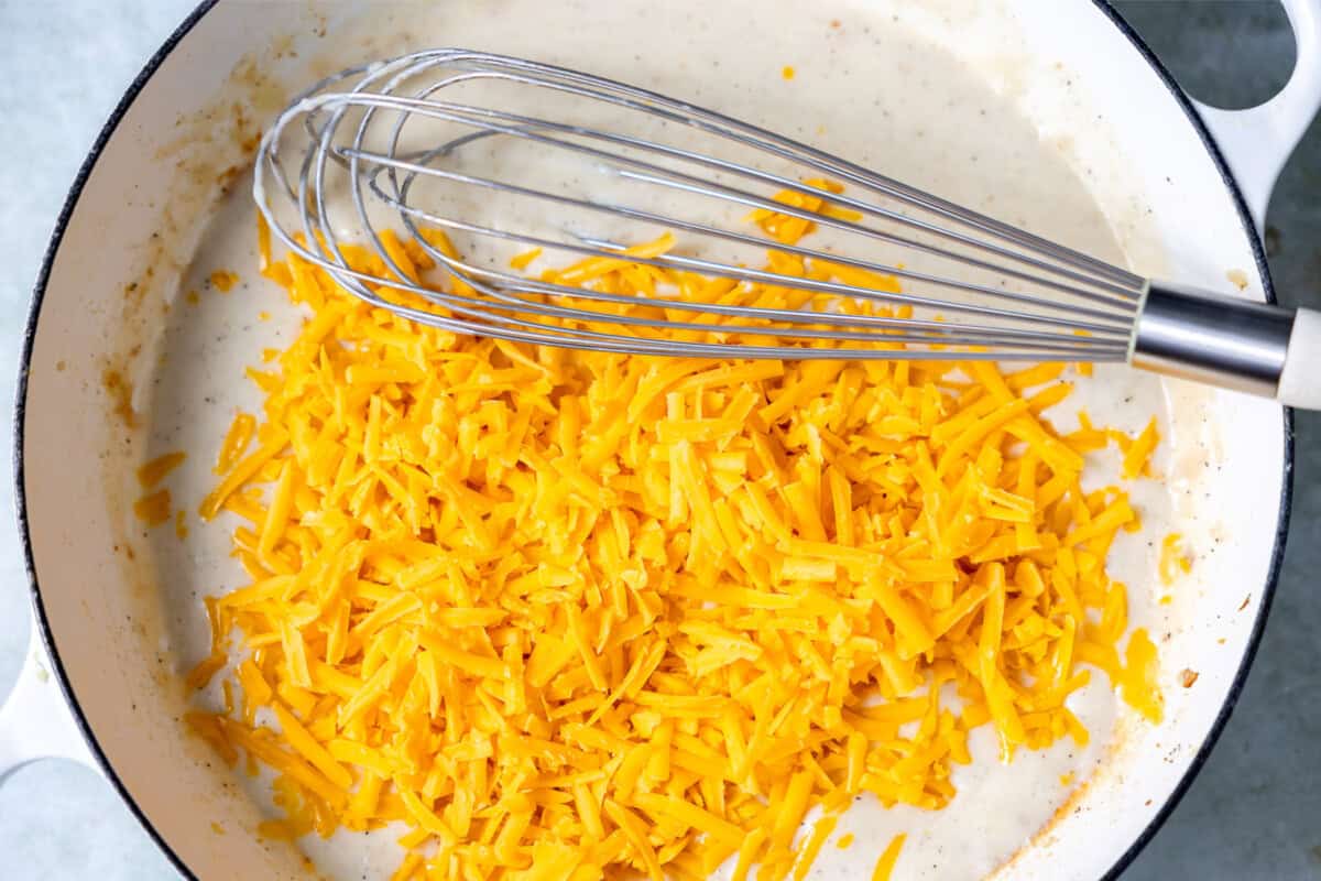 Homemade cheese sauce with a roux being cooked in a skillet. 