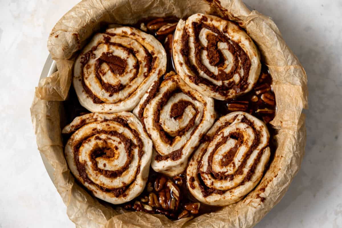 Cinnamon rolls with sticky bun topping in a baking dish before being baked. 