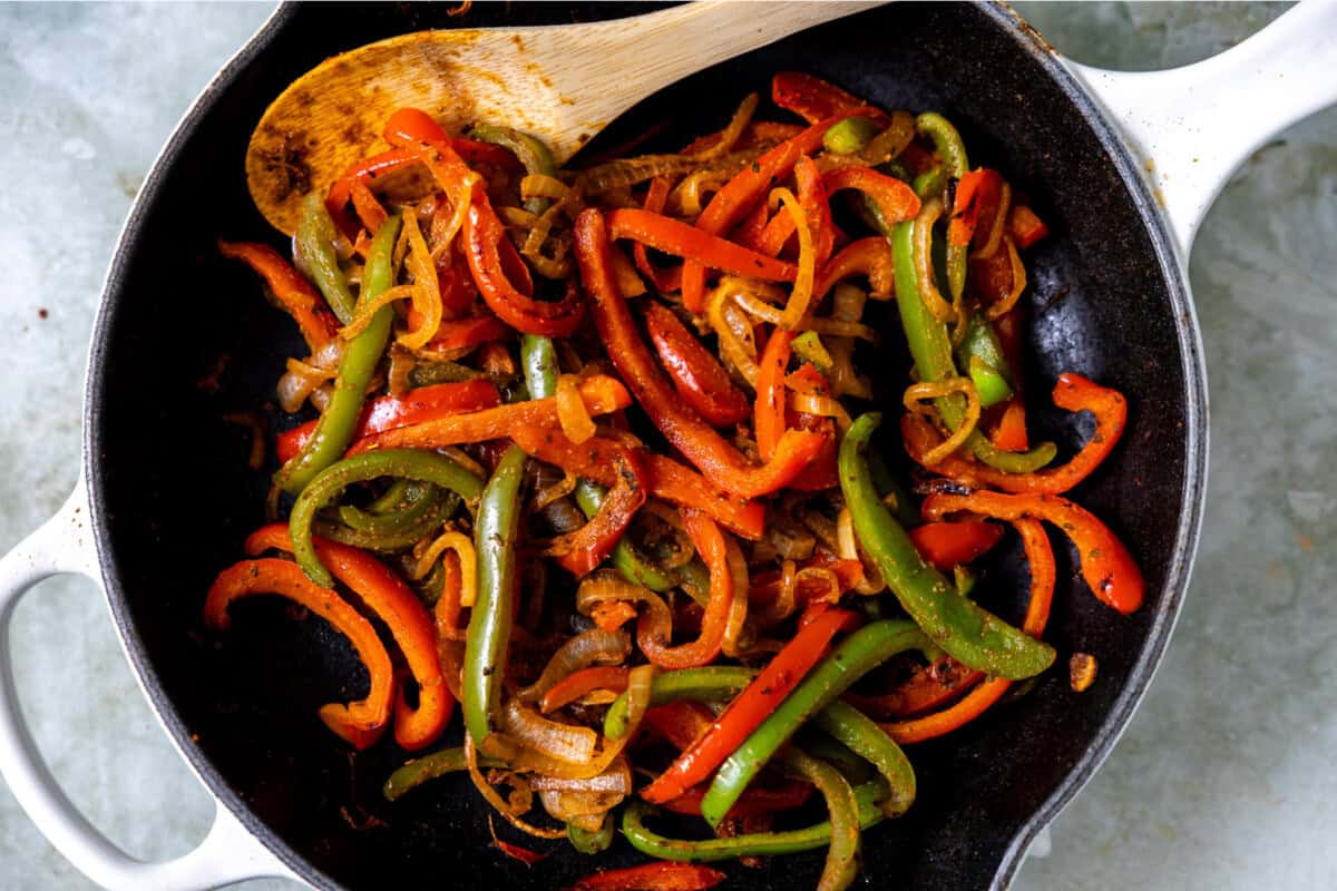 Fajita veggies being cooked in a skillet.