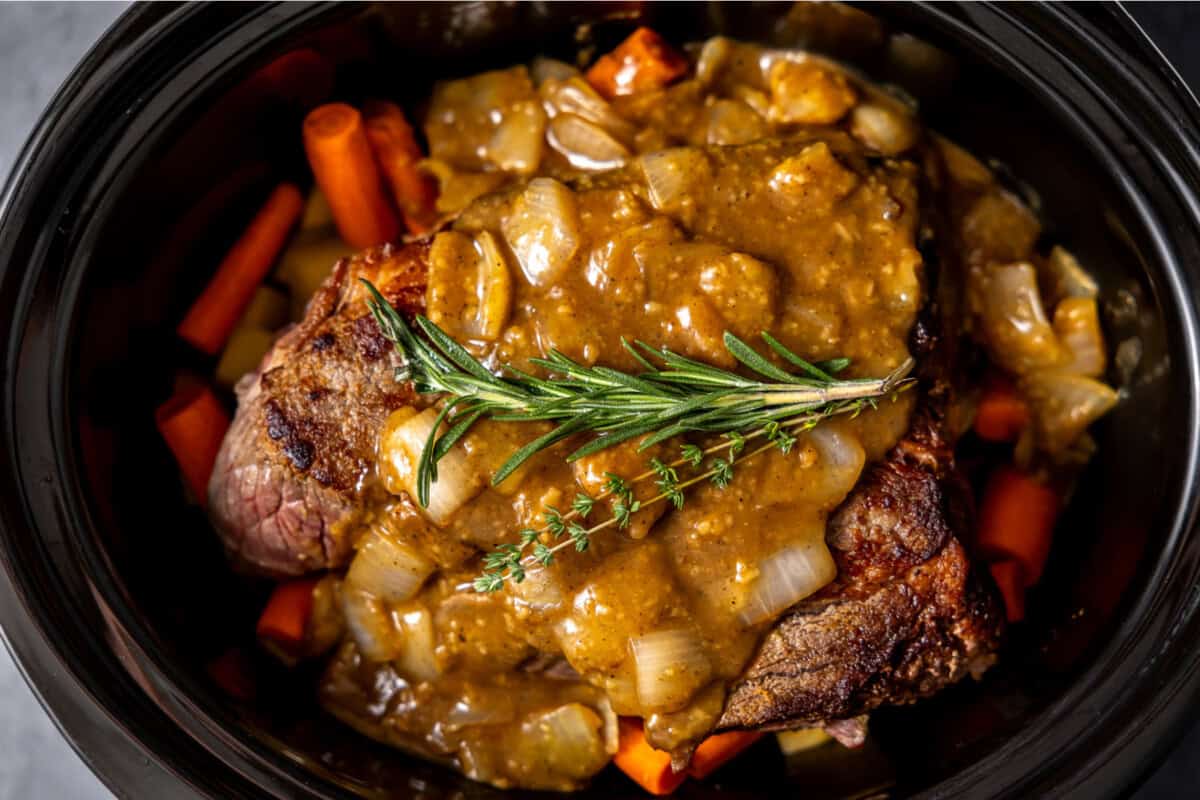 All the ingredients needed to make a pot roast in a slow cooker. 