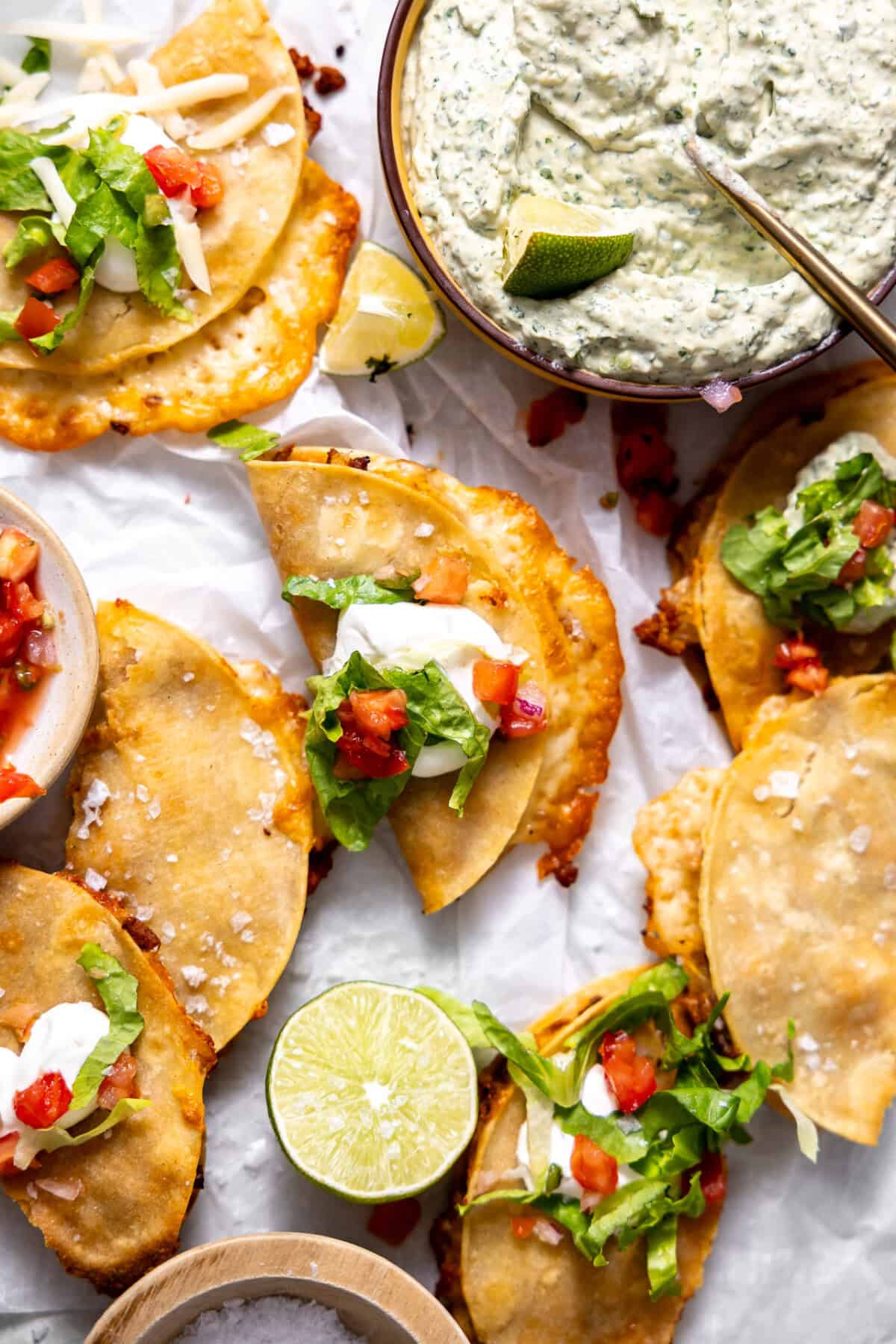 Crispy ground turkey tacos laid out with a bowl of spicy avocado dip on the side. 