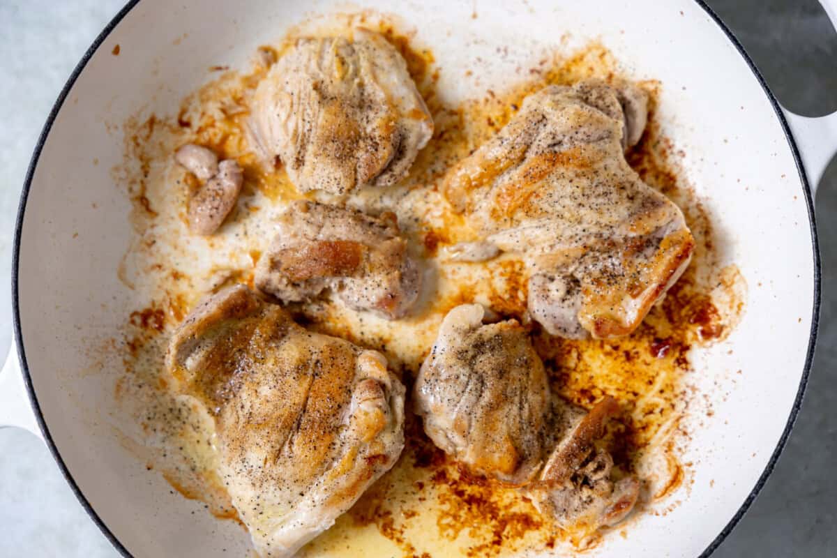 Golden-brown chicken thighs searing in a skillet, creating a flavorful base for the pot pie filling.