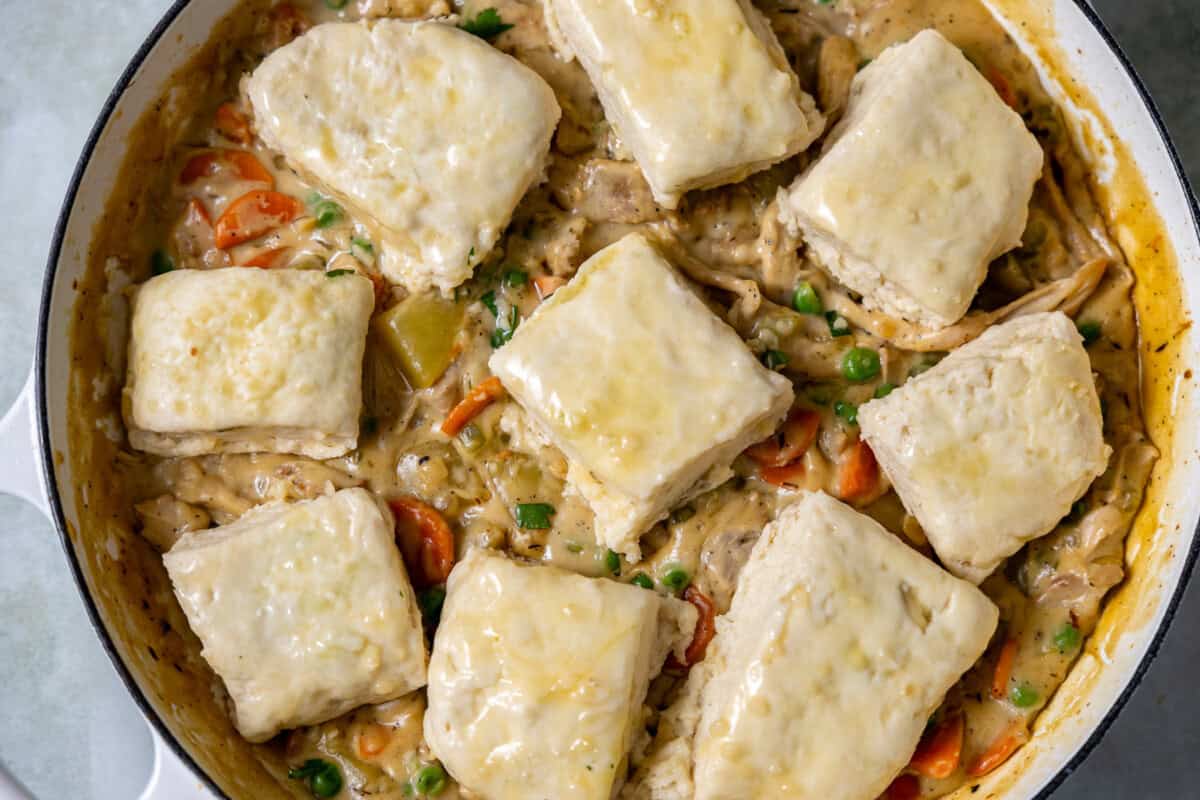 Unbaked biscuit squares arranged on top of the creamy chicken pot pie filling, just before going into the oven.