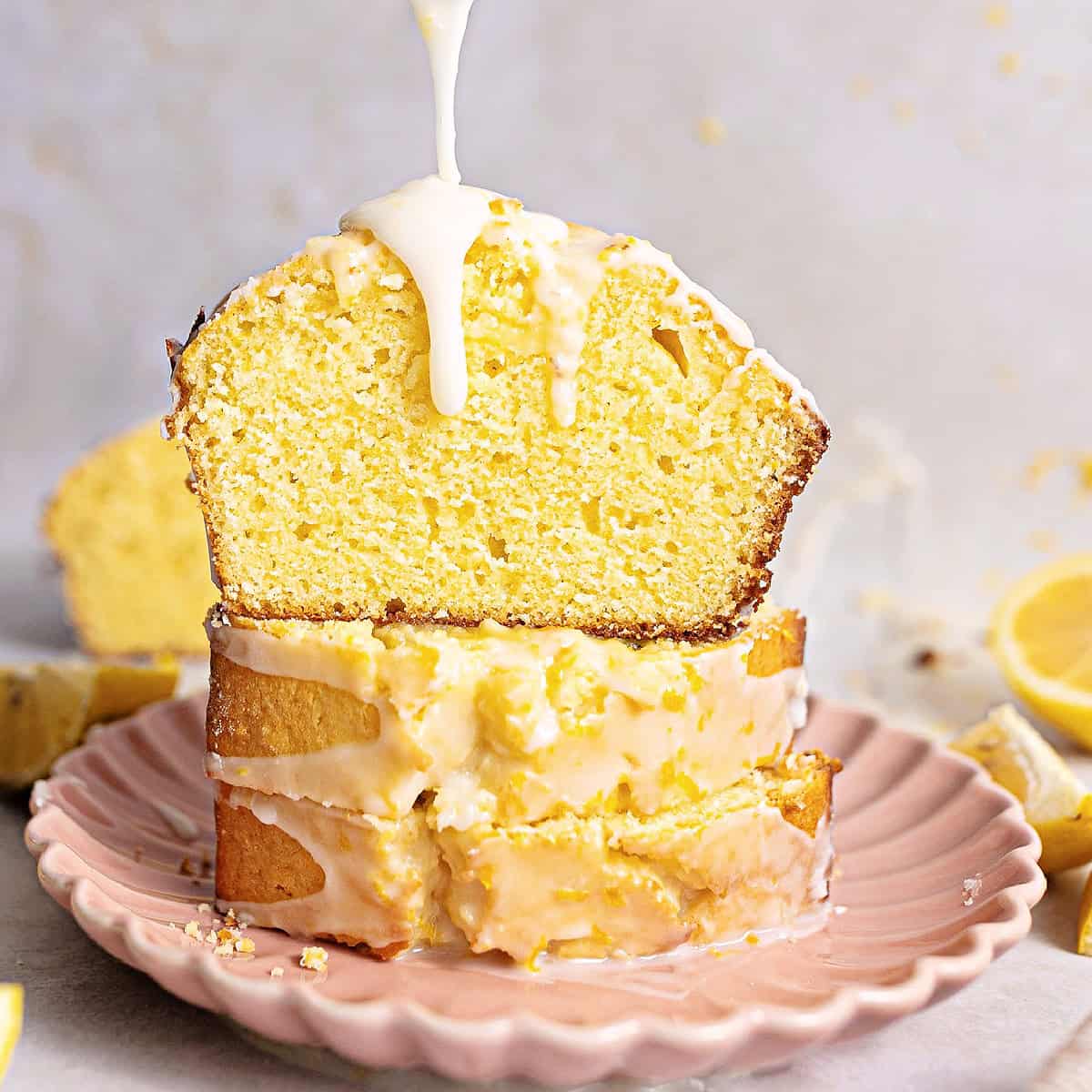 Sliced lemon loaf cake being drizzled with glaze.