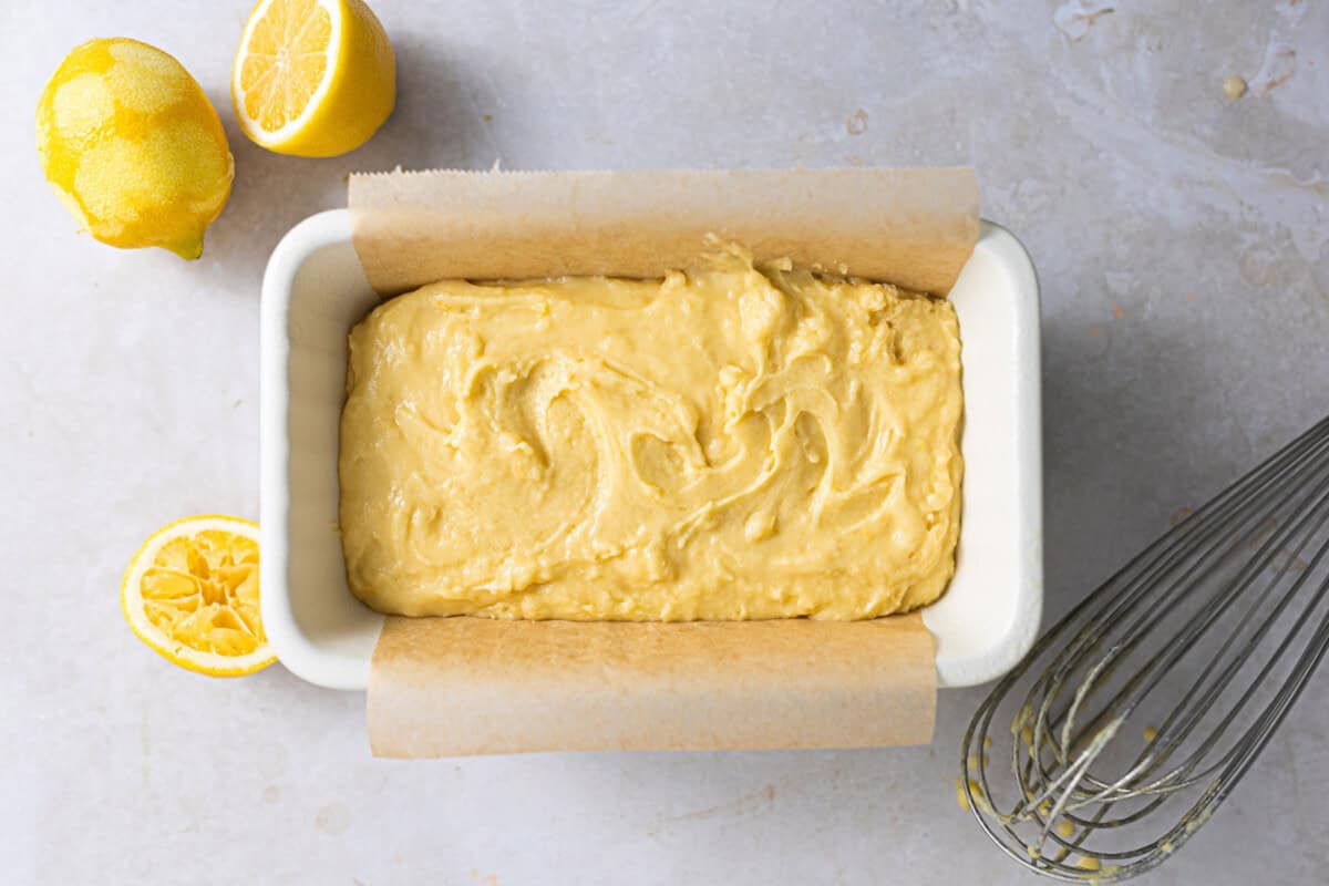 Cake batter added to a parchment lined loaf pan.