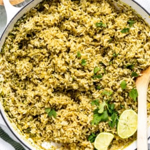 Skillet filled with Mexican green rice being served with wooden spoon.