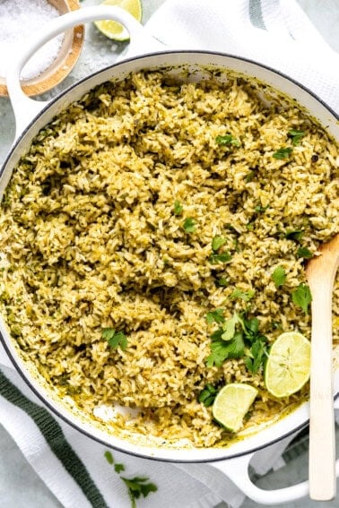 Skillet filled with Mexican green rice being served with wooden spoon.