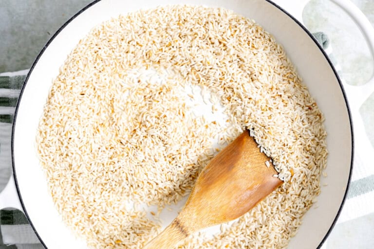 Toasting rice in a skillet with a small amount of oil.