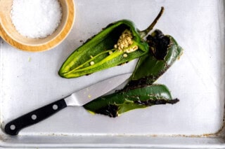 Roasted poblano being sliced in half.