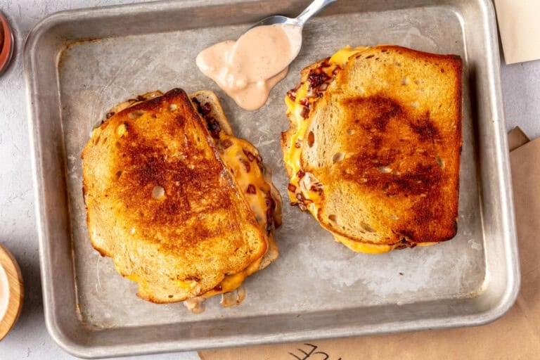 Two grilled cheese on a small baking sheet with special sauce.