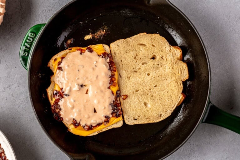 Toasting bread topped with cheese, onions, and special sauce.