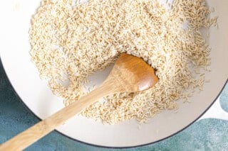 Toasting rice in a skillet with oil.