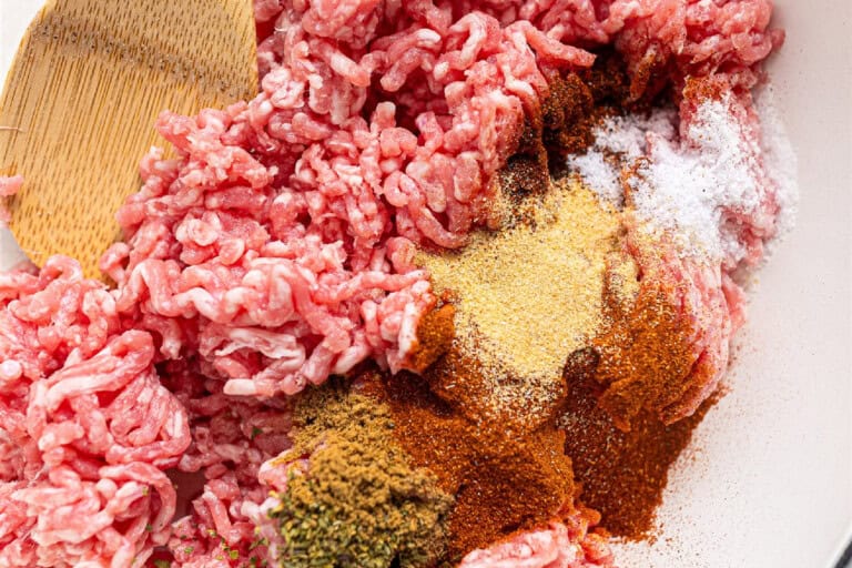 A pan with ground pork and a wooden spoon
