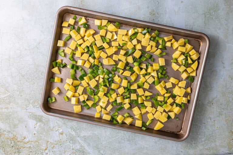 Potatoes and green bell pepper on a baking sheet.