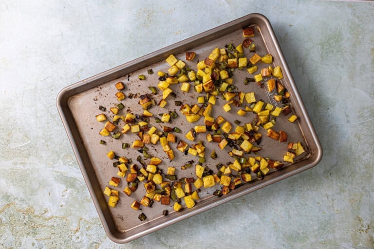 Potatoes and bell peppers on a baking sheet.