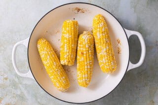 Corn in the cob in a white skillet.