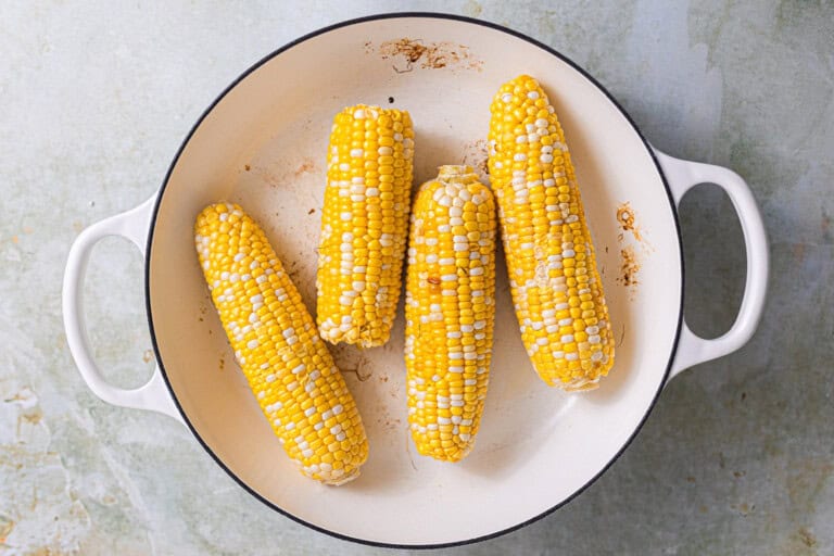 Corn in the cob in a white skillet.