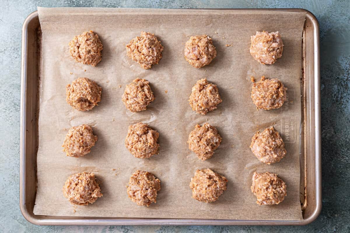Chicken meatballs laid out on a large baking sheet.