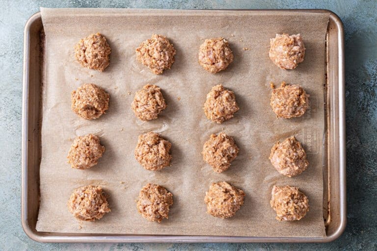 Chicken meatballs laid out on a large baking sheet.