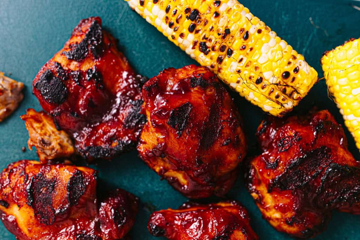 BBQ chicken and corn on a cutting board. 