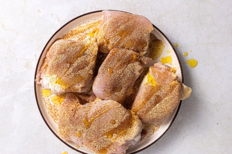 Chicken thighs coated with seasoning blend and drizzled with oil.