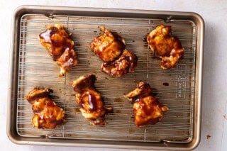 Chicken thighs brushed with bbq sauce on a baking sheet.