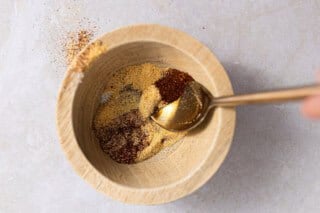 Wooden bowl with bbq seasonings in it.