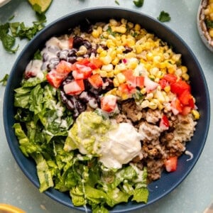 Mexican bowl with rice, beans, corn, and lettuce.