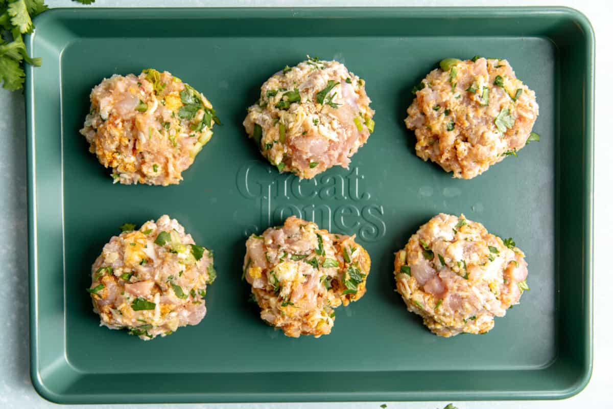 Chicken fritters formed and on a baking sheet.