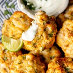 Plate of Cheesy Chicken Fritters with a cilantro dipping sauce.