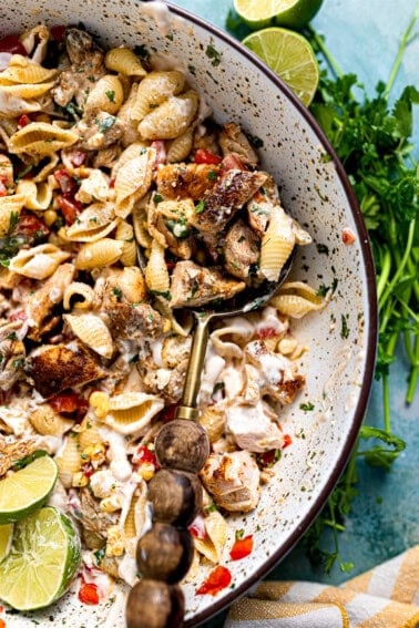 Chicken taco pasta salad served in a bowl with a wooden handled spoon.