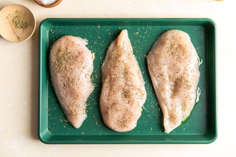 Seasoned chicken breasts on a baking sheet.