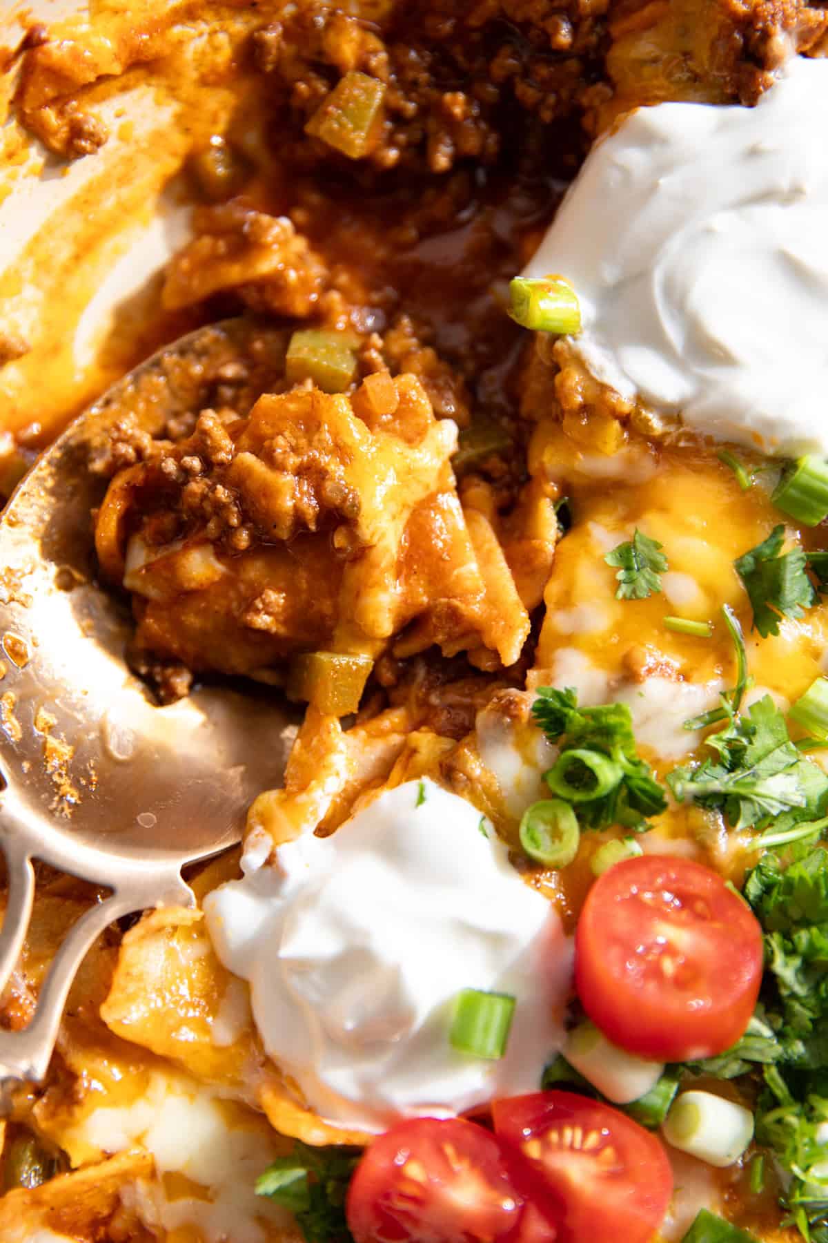 Spoon serving up ground beef enchilada skillet. 