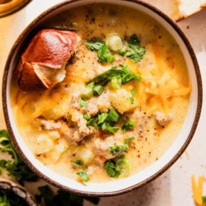 Bowl of potato and sausage beer cheese soup served with pretzel bread.