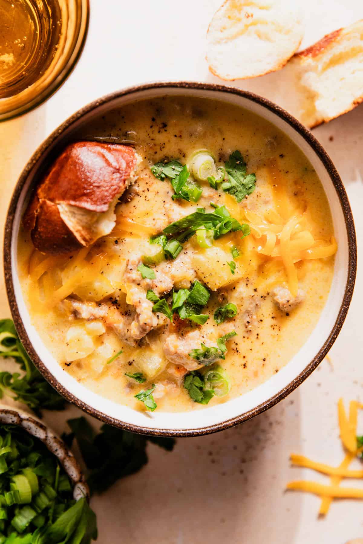 Bowl of potato and sausage beer cheese soup served with pretzel bread.