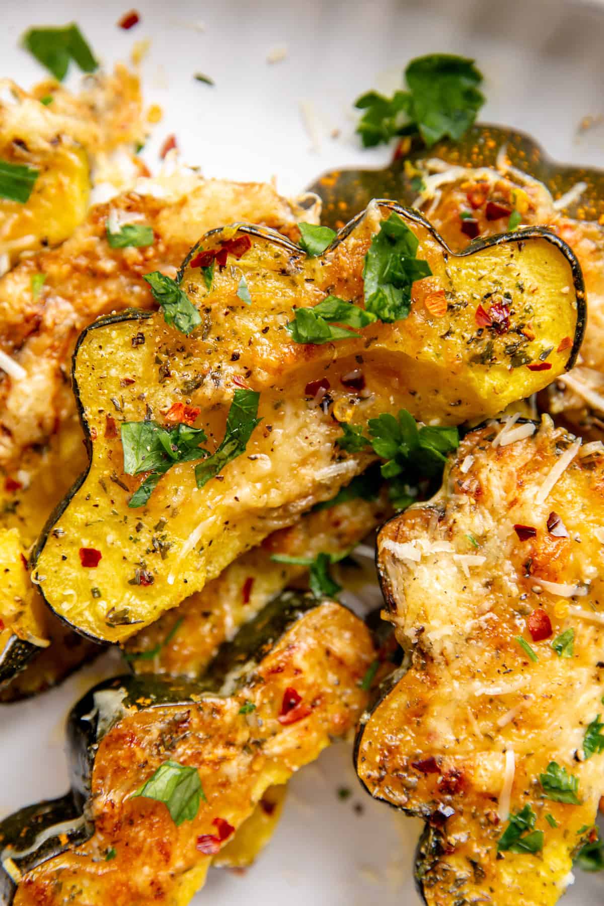 Roasted acorn squash topped with garlic and parmesan on a plate.