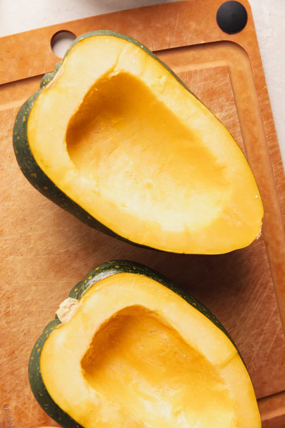 Halved acorn squash with seeds removed.