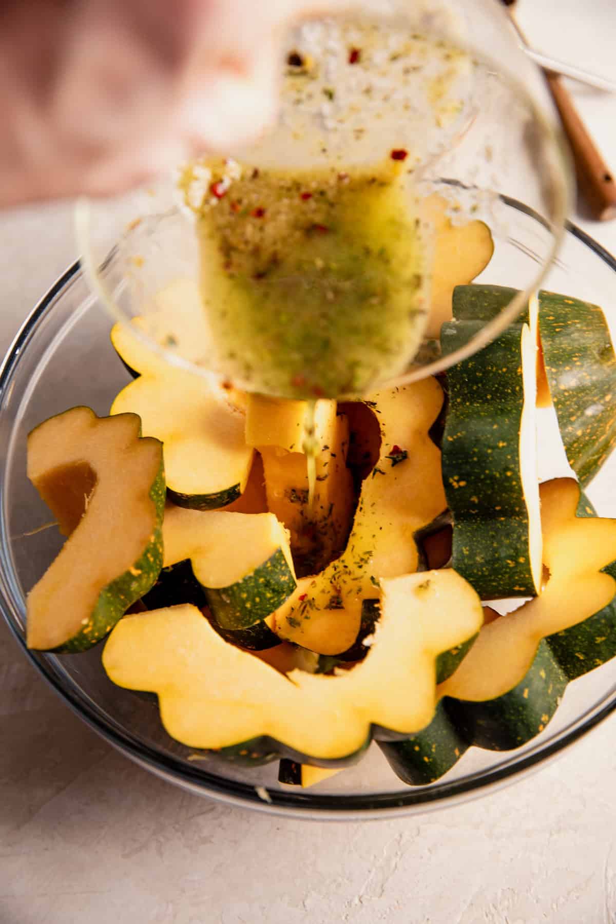 Pouring garlic herb mixture on top of acorn squash.