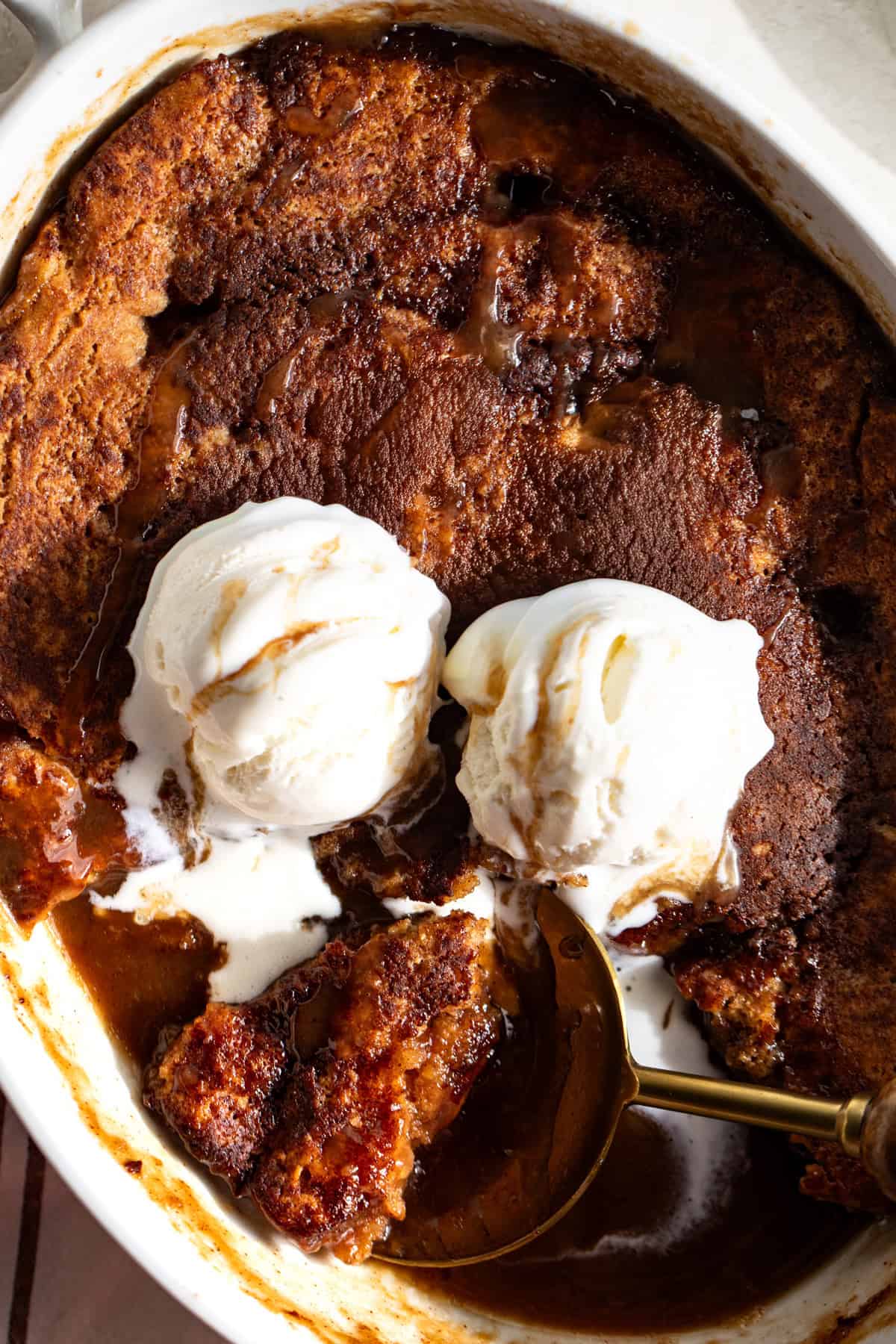 Snickerdoodle cobbler in a baking dish topped with scoops of vanilla ice cream. 