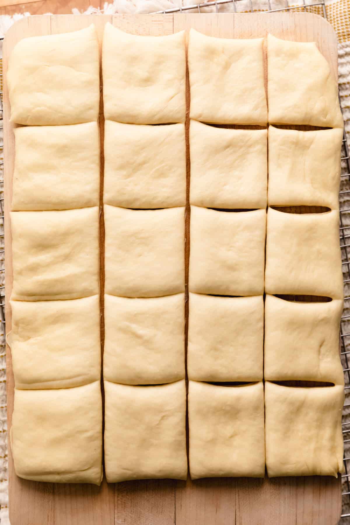 Bread roll dough that has been pressed out into a rectangle and cut into square bread rolls.
