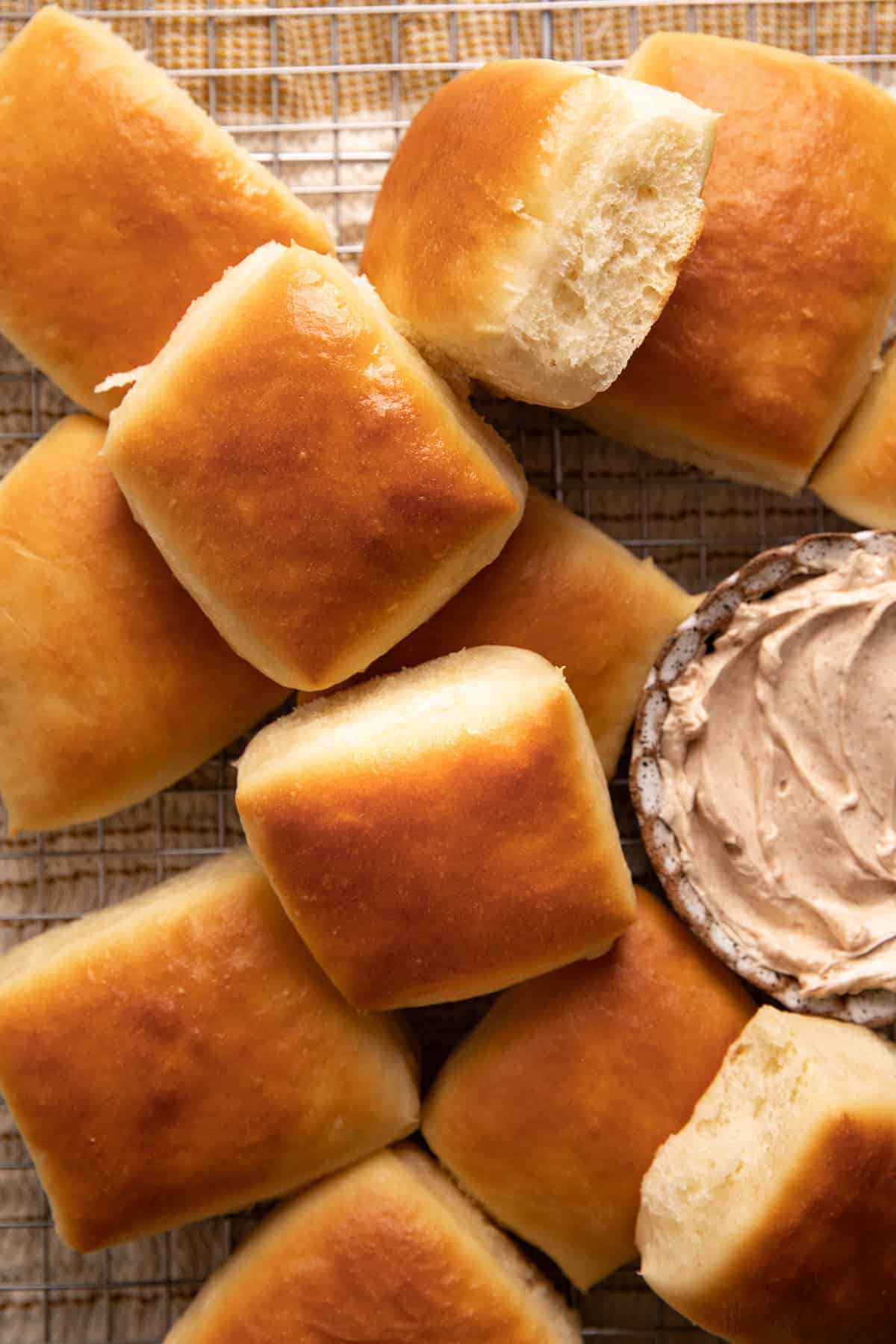 Texas Roadhouse rolls stacked on a wire rack with a bowl of cinnamon honey butter.
