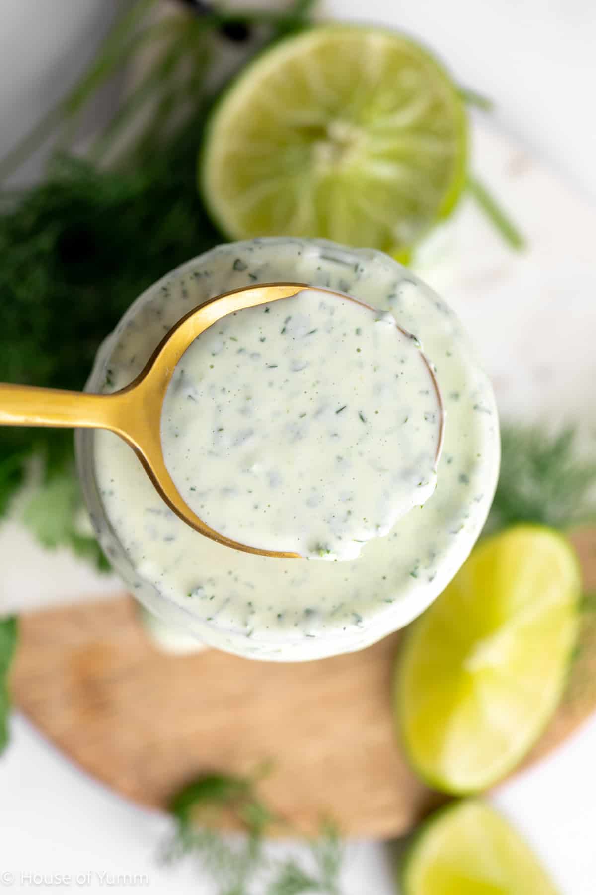 Cilantro lime ranch in a jar with a spoon scooping it up.