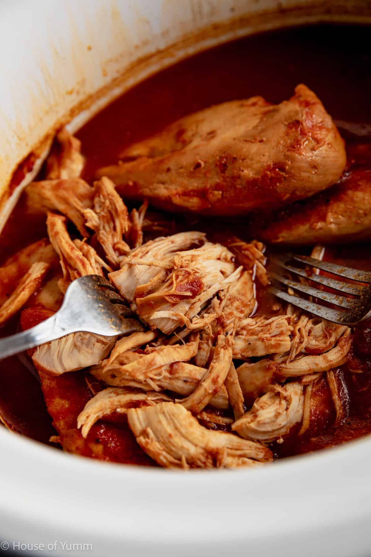 Shredding chicken in a slow cooker with two forks.
