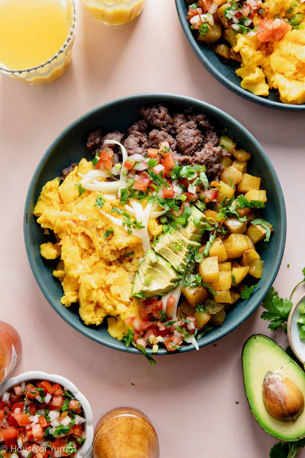 Breakfast burrito bowl made with scrambled eggs, sausage, and potatoes, topped with avocado and salsa.